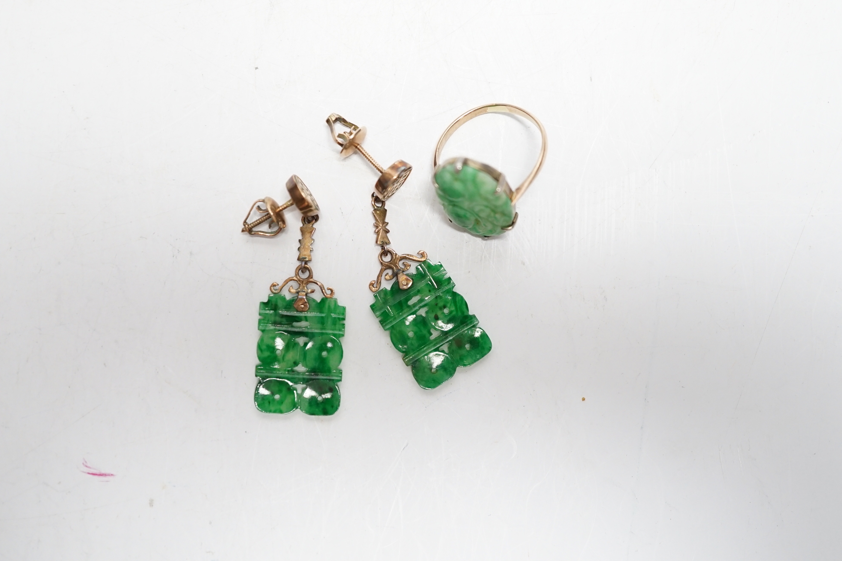 A pair of Chinese 14k yellow metal and jade set drop earrings, 37mm and a yellow metal and carved oval jade set ring, gross weight 6.1 grams.